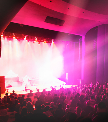 Stage with pink lights and the silhouette of an audience watching