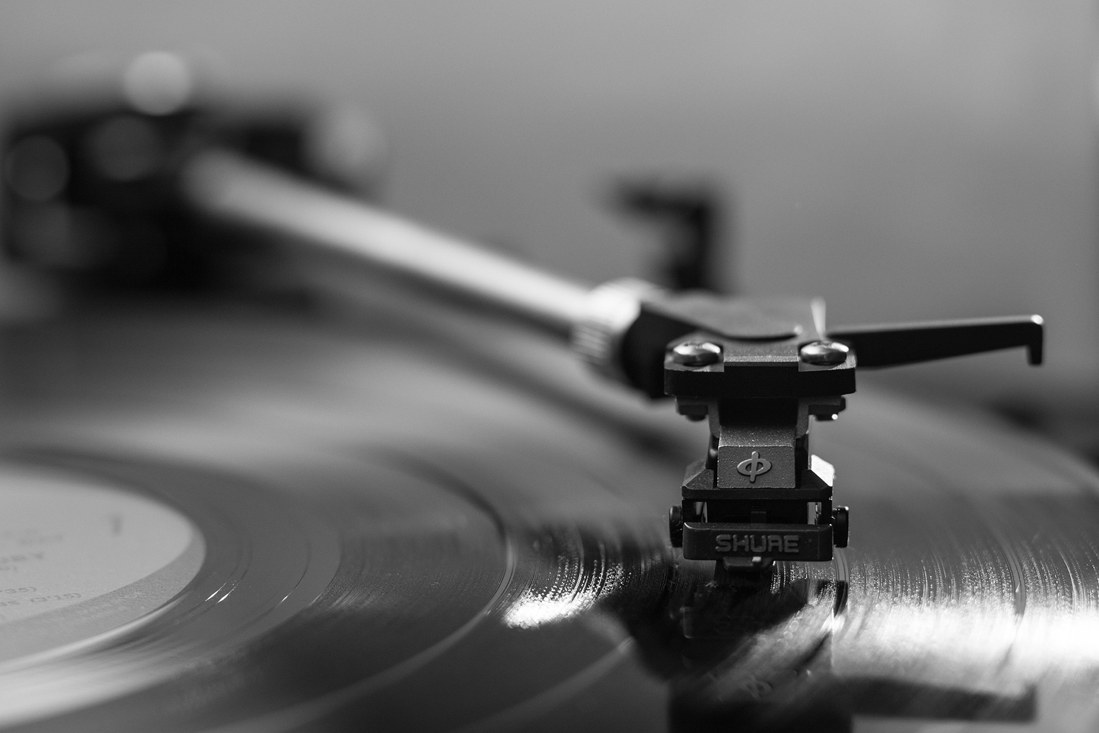Black and white close up of a vinyl record on a turntable