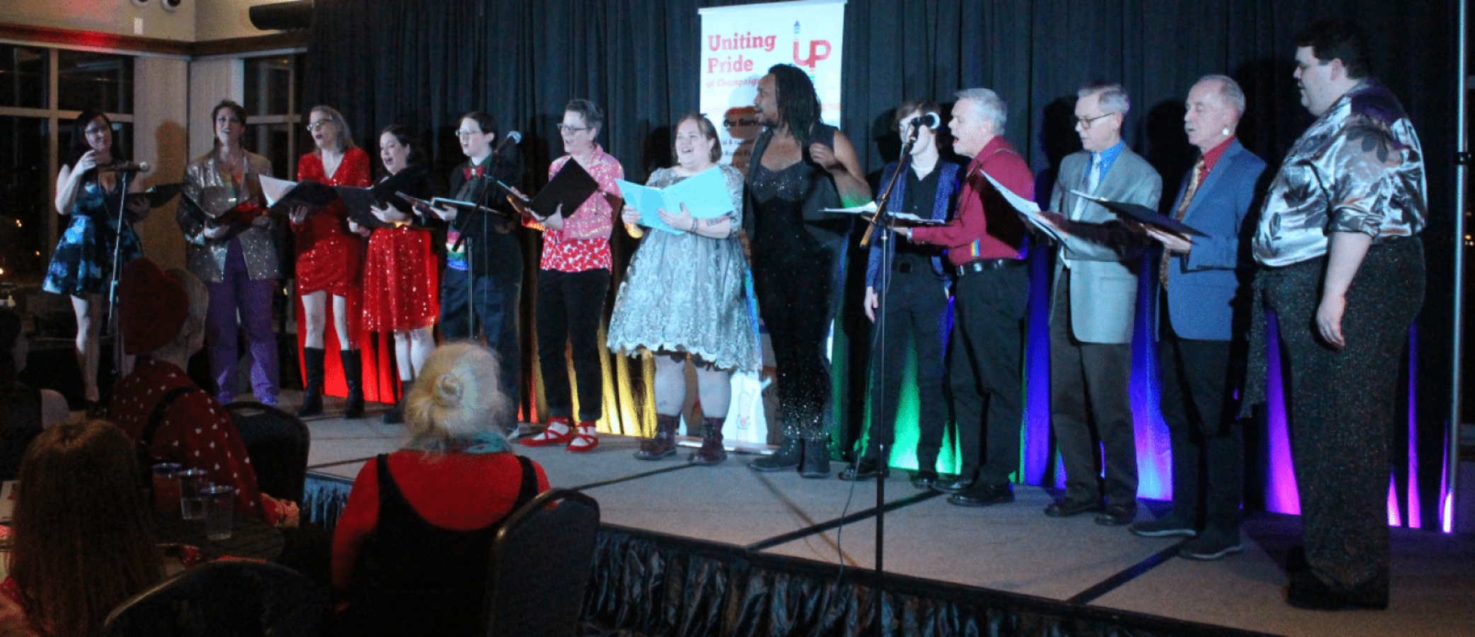 Thirteen vocalists on a stage singing as a choir