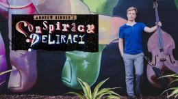 Man with a bass standing next to a wall mural and a sign that says Conspiracy Deliracy