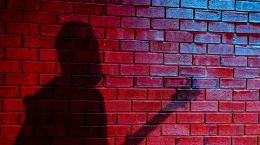 Silhouette of guitar player against brick wall 