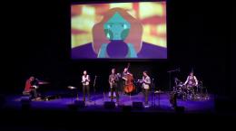 The Queen's Cartoonists perform live onstage with animated movie in background 