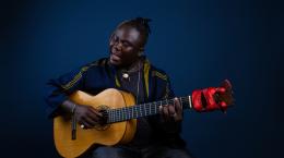 Black man singing and playing acoustic guitar