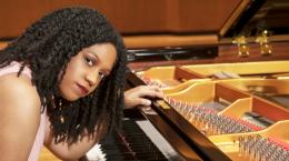 Rochelle Sennet, a Black woman in a pink sleeveless blouse seated at a piano