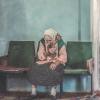 photo of an old white Ukrainian woman in a white headscarf sitting in a chair