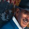 Image of a man wearing a suit and a hat, smiling at the viewer.