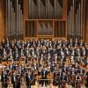 an orchestra stands for a formal portrait on a grand stage