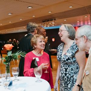 Man and two women standing at table laughing