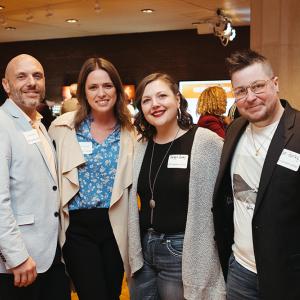 Two women and two men wearing name tags pose near Stage 5 Bar